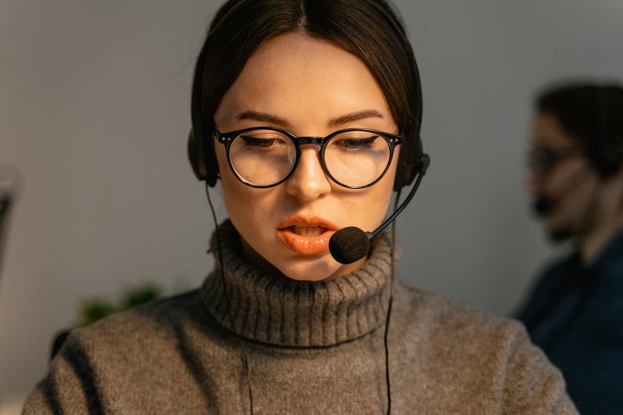 Close-up of a focused call center agent with eyeglasses and headset providing customer support.